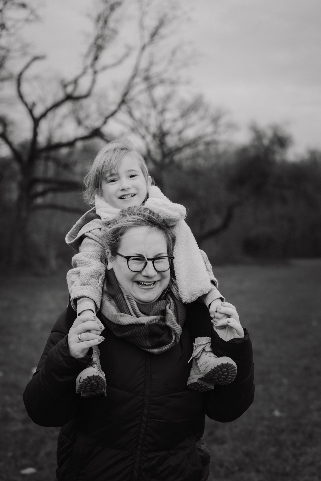 Mädchen sitzt auf den Schultern ihrer Mama beim Familienfotoshooting in der Natur in Köln