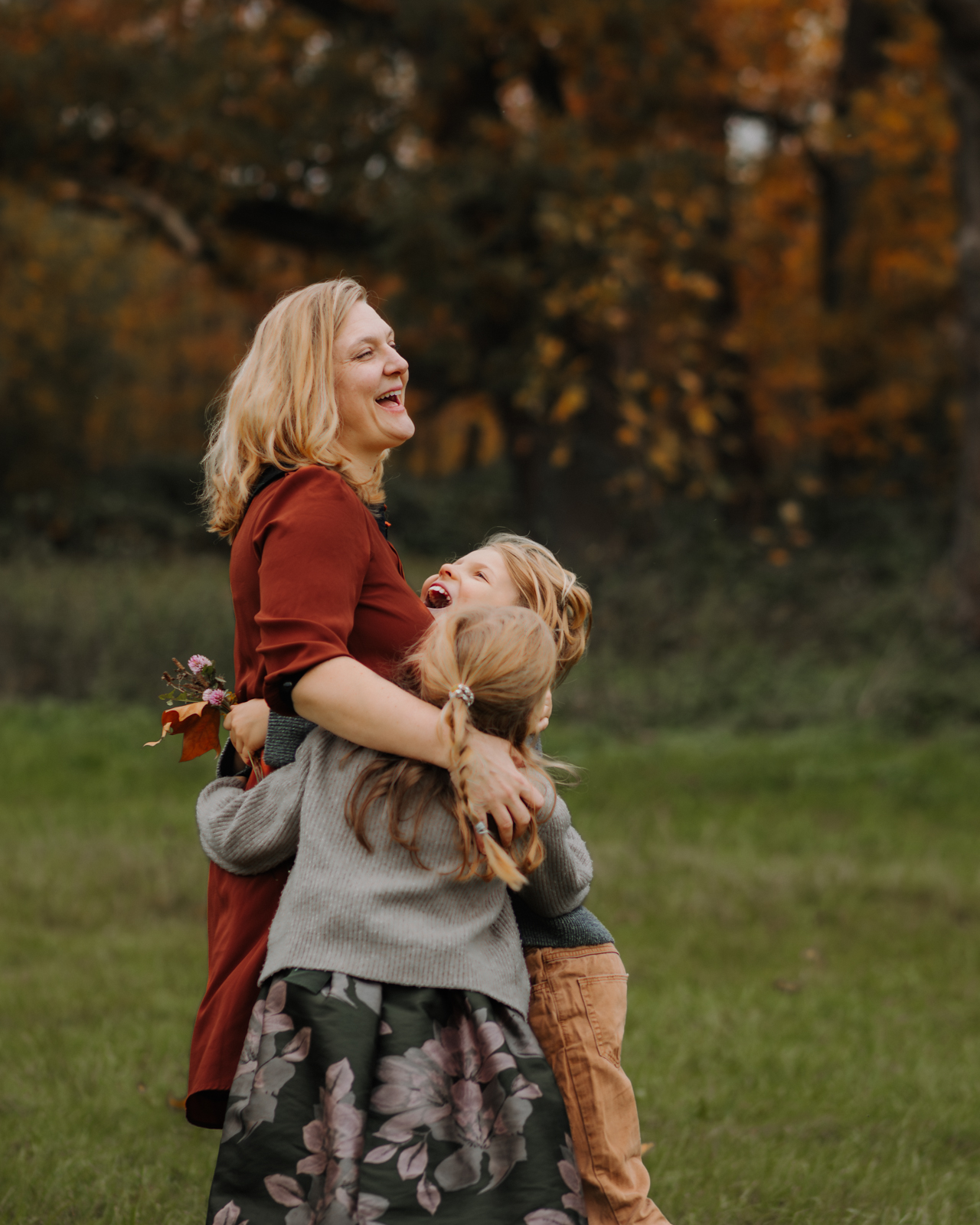 Mama wird bei Fotoshooting von ihren beiden Kindern umarmt und lacht von Herzen