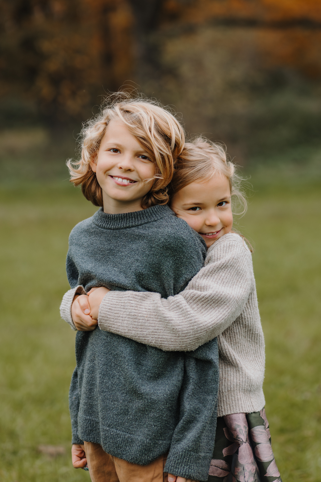Mädchen umarmt ihren großen Bruder bei Fotoshooting im Park