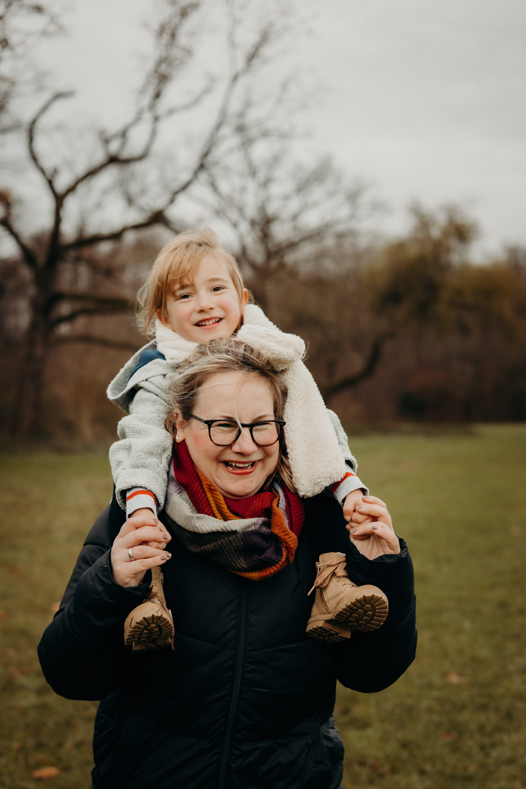Mädchen sitzt auf Mamas Schultern und beide freuen sich
