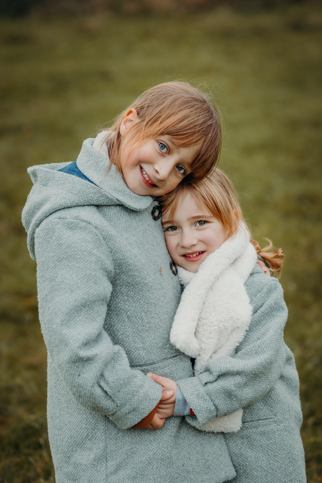 Zwei Schwestern umarmen sich liebevoll auf Wiese