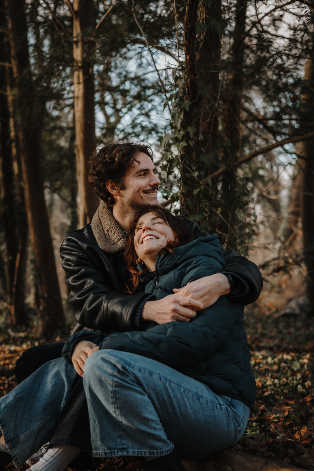 Natürliches Paar Fotoshooting Köln – Paar sitzt eng umschlungen im Wald