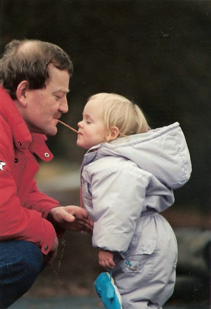 Papa und kleine Tochter essen Salzstange mit geschlossenen Augen