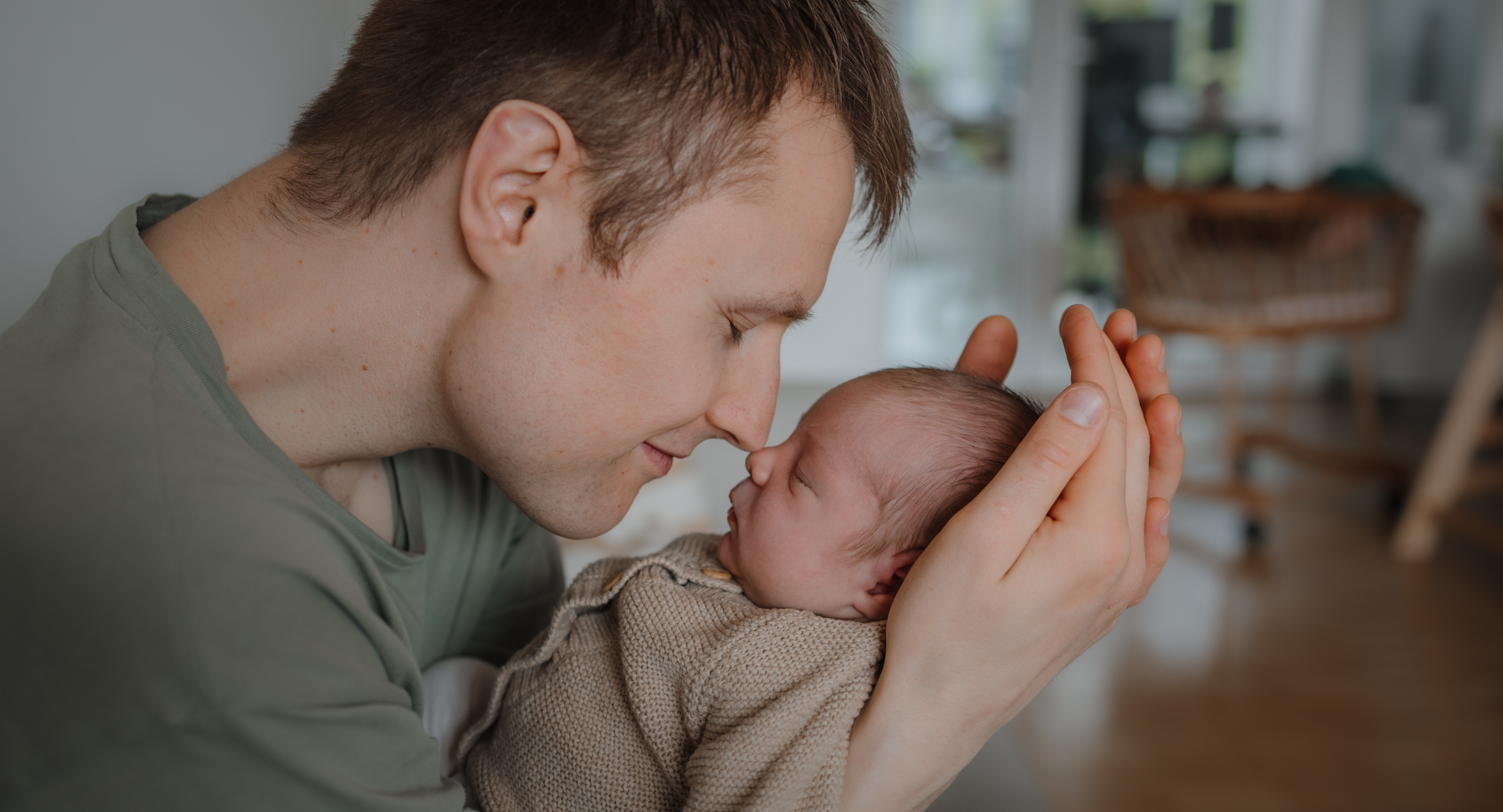 Papa und neugeborenes Baby berühren sich sanft mit den Nasen